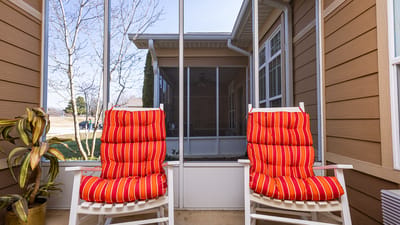 Two red striped chairs on a screened porch.