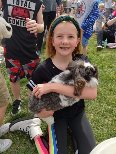 Child holding a rabbit at a community event.