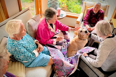 Residents interacting and petting a dog in a common area.