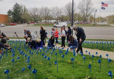 Community gathering with blue pinwheels in a grassy area