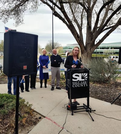 A speaker at an outdoor event with attendees.
