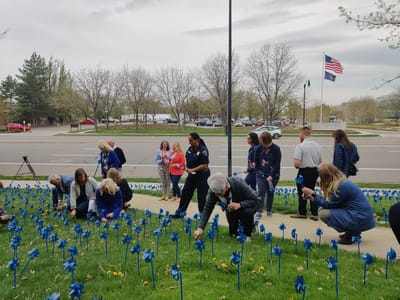 Group gathering outdoors planting blue pinwheels.