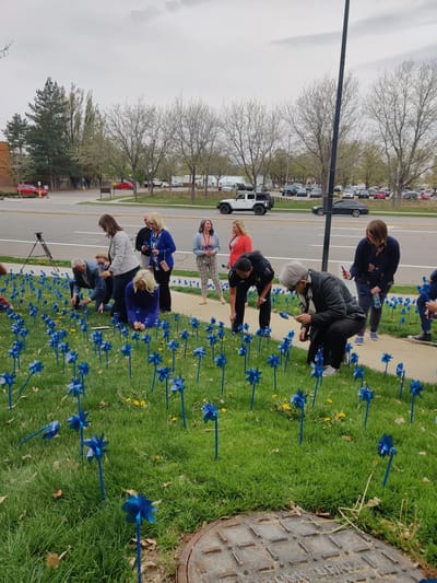 Participants planting blue pinwheels in a garden