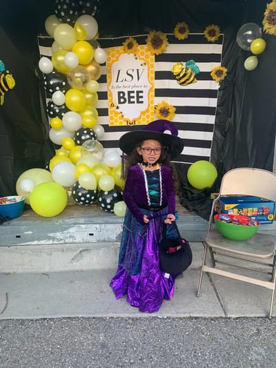 Child in a witch costume at a colorful event