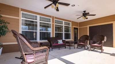Outdoor seating area with wicker chairs and ceiling fans.