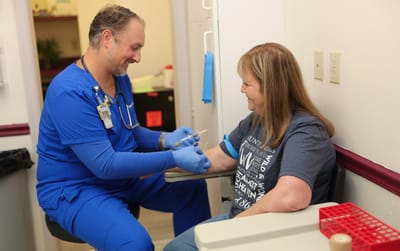 Nurse assisting a resident with a medical procedure.