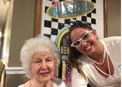 A resident and staff member smiling together.