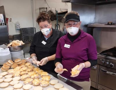 Two staff members preparing meals in the kitchen.