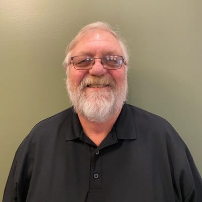 Smiling elderly man with glasses, dark polo shirt