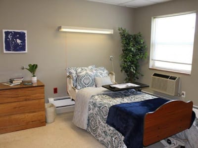 Cozy resident room with bed, air conditioner, and decor