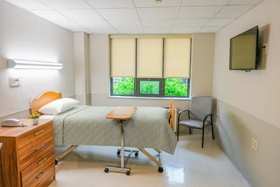 Private room in a nursing facility with a bed and chair