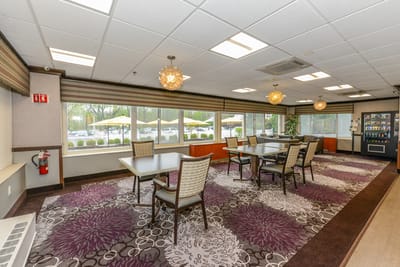 Common area with tables and chairs near large windows