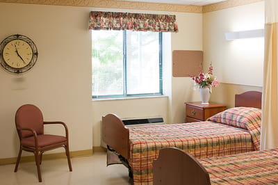 A cozy resident room with two beds and a clock