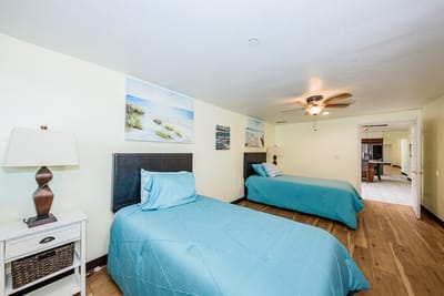 Brightly lit bedroom with two beds and beach-themed decor