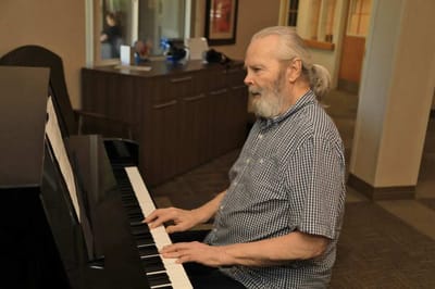 Elderly man playing piano in a common area