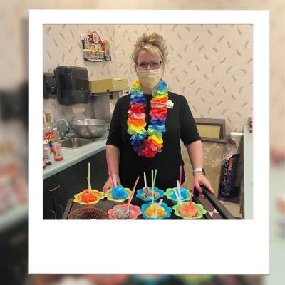 Staff member serving colorful treats in the kitchen.