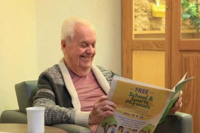 Elderly man reading a newspaper in a lounge