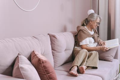 Senior woman reading a book on a couch