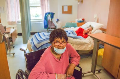 Townhouse Center for Rehabilitation & Nursing, Nursing Home in Uniondale, NY — Resident in a wheelchair smiling in a nursing room