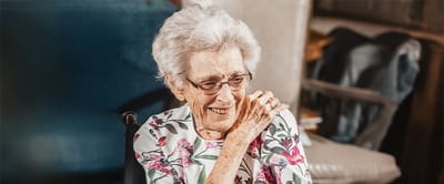 Elderly woman smiling, enjoying the moment.