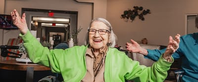 Happy elderly woman celebrating in a communal space.