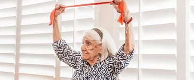 Senior woman exercising with resistance band indoors