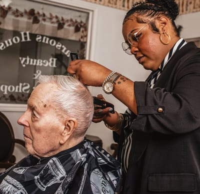 Hair stylist giving a haircut to an elderly man.