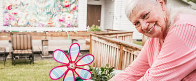 Senior woman gardening outdoors with a colorful flower decoration.