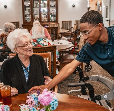 Engaging interaction between staff and resident in a dining area.