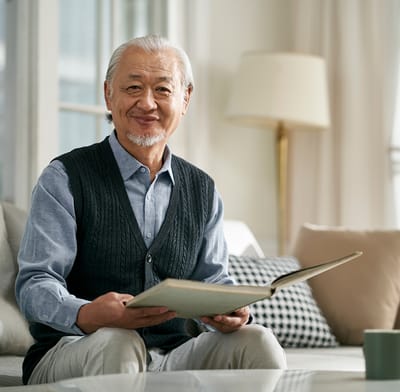 Senior man reading a book in a cozy living room.