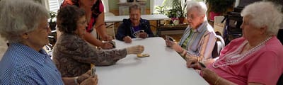 Seniors playing cards together in a common area.