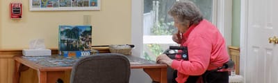 Senior woman working on a puzzle at a table.