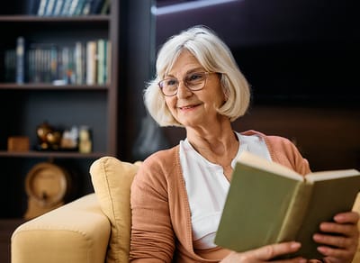 Senior woman reading a book in a cozy setting.