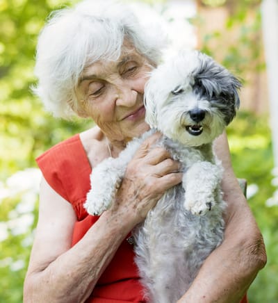 Elderly woman happily holding a small dog.