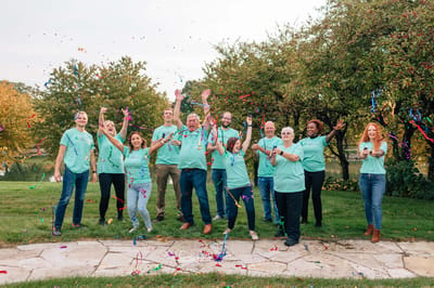 Staff celebrating outdoors with confetti.