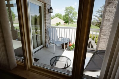 A porch view with chairs and potted flowers.