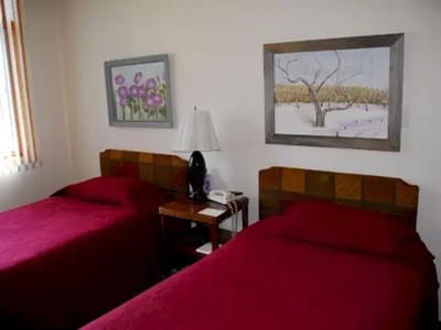 Two twin beds with red bedspreads and artwork