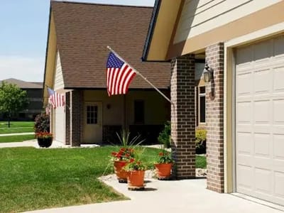 Front exterior of a facility with American flags and flower pots.