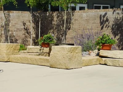 Outdoor seating area with stone benches and plants.
