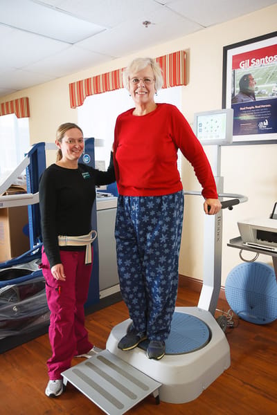 Staff assisting resident on a fitness balance machine.