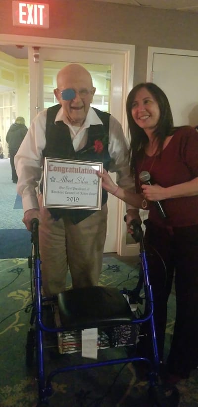Resident celebrating with staff and award.