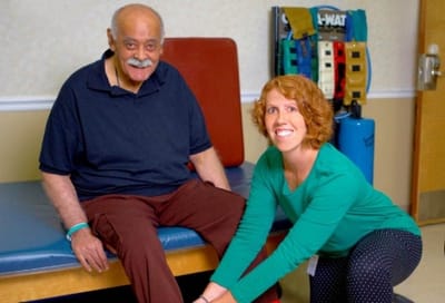 Physical therapy session between a resident and staff.