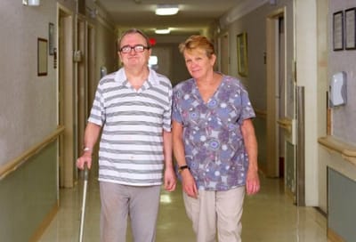 A resident and staff member walking in a hallway