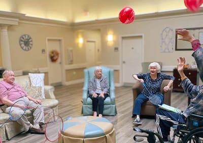 Residents enjoying a game with balloons indoors.