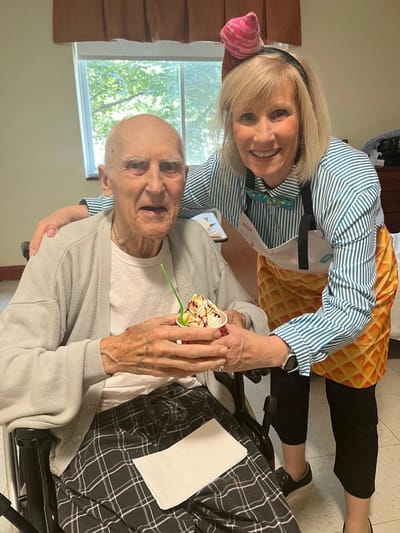 A resident enjoys ice cream with staff member.