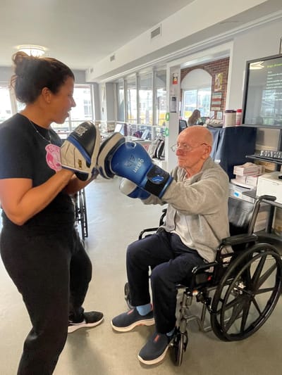 Resident engages in boxing training with staff member.