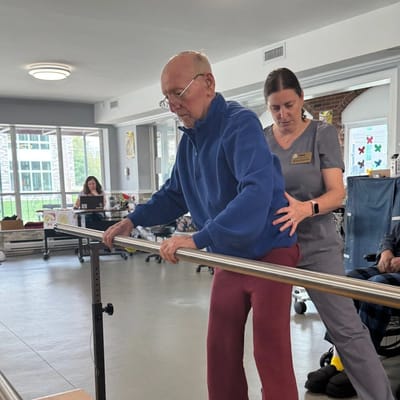 A staff member assisting a resident with rehabilitation.