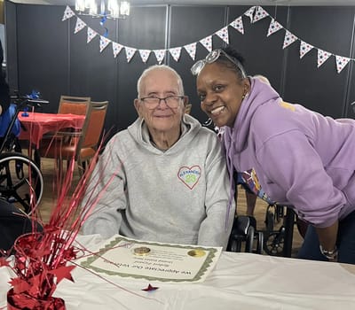 Resident and staff member celebrating at a decorated table.