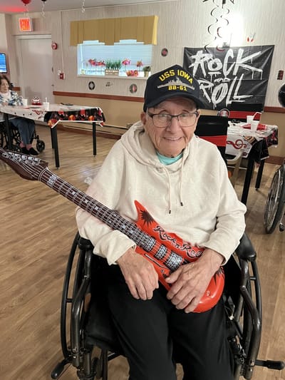 Resident enjoying a musical activity with a toy guitar.