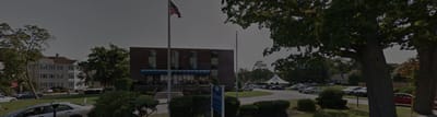 Exterior view of the rehabilitation center with vehicles and flags.